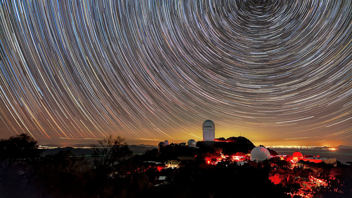 A timelapse photograph of a telescope with stars rotating in the background.